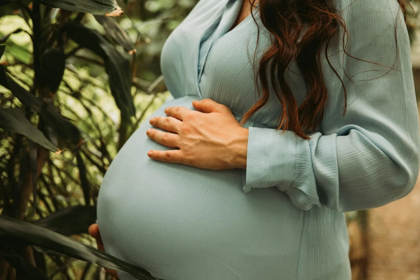 Przyszła mama w błękitnej sukience wśród drzew